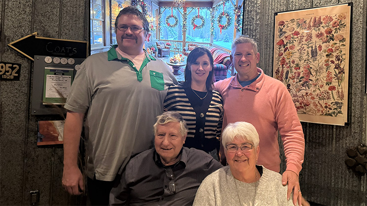 Family posing together inside a cozy restaurant decorated with holiday wreaths and framed artwork